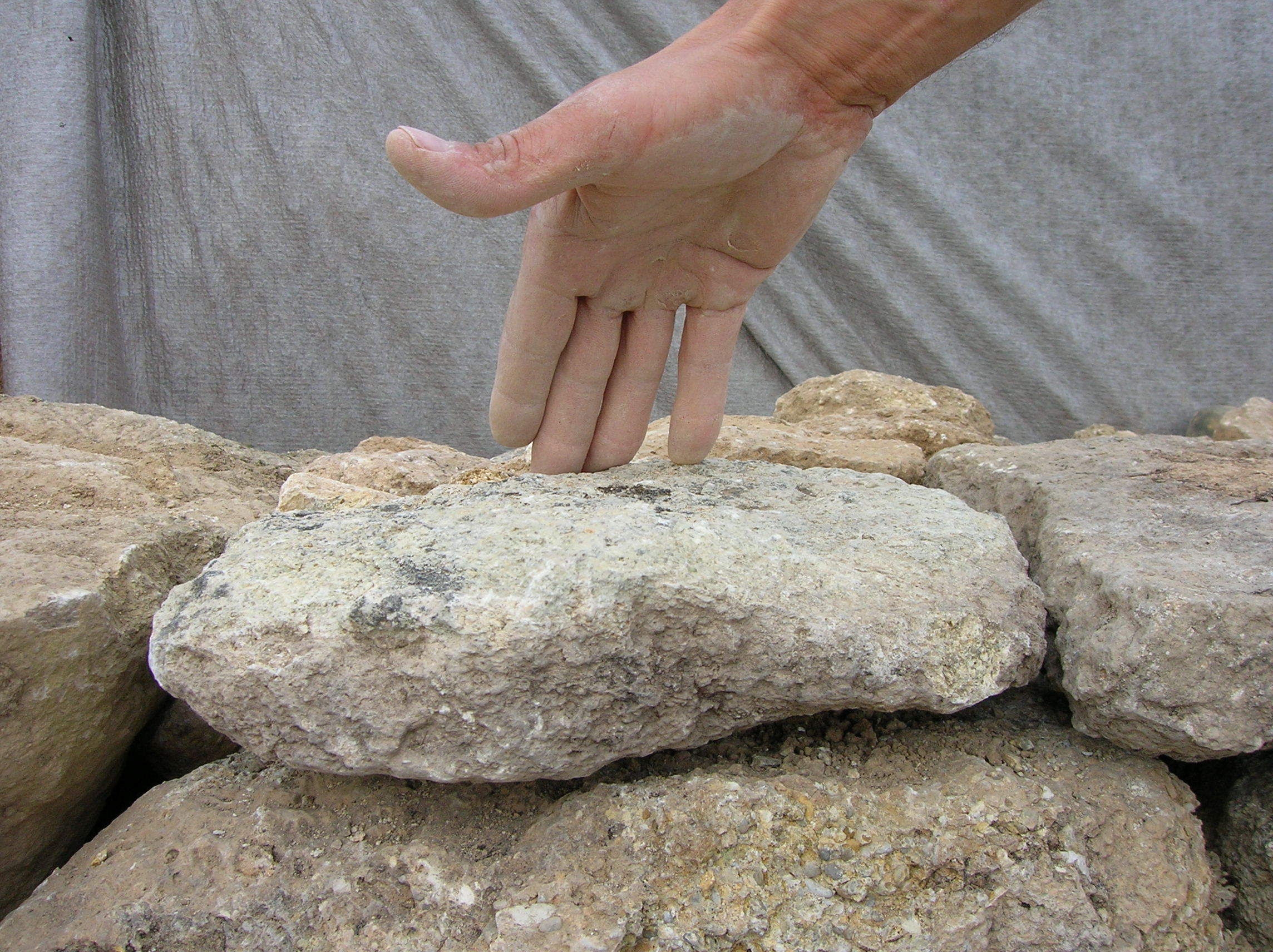 Geste lié à la vérification de l’assise de pose d’une pierre et de son équilibre sur le rang de dessous. L. Cagin – L. Nicolas, 2008 © (Association Une pierre sur l’autre)